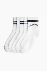 Pack de cinco pares de medias blancas de algodón con puño acanalado y borde superior elástico. Incluye diseños con rayas horizontales en negro y gris, y con la inscripción 'LES SPORTS' en negro.