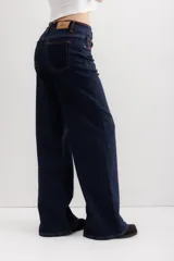 Pantalón de jean azul oscuro, de corte wide leg, con cintura alta y detalles de costuras en marrón.