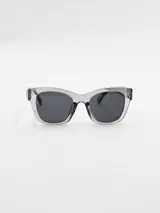 Lentes de sol de acetato color gris transparente, con forma cuadrada y detalle de corazón dorado en el lateral.