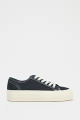 Zapatillas bajas de denim azul oscuro con cordones blancos y suela de plataforma color crema.