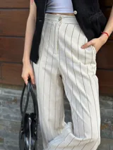 Pantalón de vestir color beige con finas rayas verticales negras, de corte recto y tiro alto.