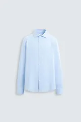 Camisa celeste a rayas verticales blancas, de corte recto, con cuello italiano abierto, mangas largas con puños abotonados y cierre frontal con botones.