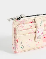 Tarjetero color crema con estampado de flores rosas y verdes, cierre con broche a presión y compartimento superior con cierre.