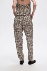 Pantalón slouchy de viscosa con estampado floral en tonos beige y negro, bolsillos laterales, cintura alta y detalle de punto smock en los tobillos.