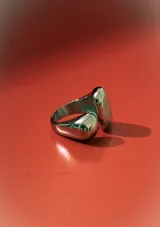 Anillo plateado con diseño orgánico y moderno, compuesto por dos formas abultadas y lisas que se unen en la banda.