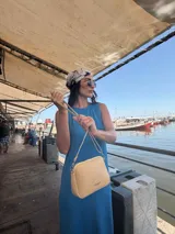 Bandolera pequeña color negro, de material símil cuero, con correa fina y herrajes plateados.