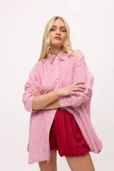 Camisa oversize a rayas verticales color amarillo y blanco, con cuello camisero, manga larga y cierre frontal con botones.