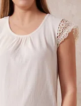 Blusa color beige en tejido elastizado, con cuello redondo y mangas cortas con aplique de crochet.