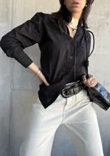 Camisa negra con bordado floral, de manga larga y corte recto.