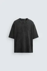 Camiseta negra de corte holgado confeccionada en tejido de algodón con cuello redondo y manga corta. Presenta un efecto lavado que le da una apariencia única.