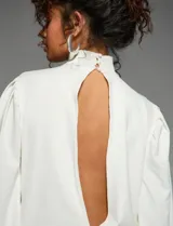 Vestido corto blanco de manga globo con cuello cruzado profundo en V, volantes y efecto drapeado.