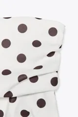 Top blanco con estampado de lunares negros, escote recto, hombros descubiertos y detalle de frunces.