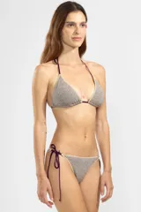 Bombacha de bikini confeccionada en tejido lurex color champagne con brillo sutil. Corte triángulo clásico con terminaciones en overlock y tiras laterales ajustables, finalizadas con los dijes insignia de Polonio.