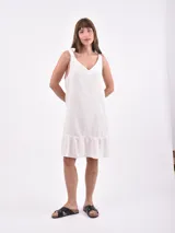 Vestido corto blanco de lino, con breteles con lazo y falda con volados.