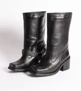 Bota de cuero color marrón oscuro, de caña media, con hebilla y tachas decorativas.