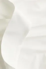 Top blanco sin mangas de punto elástico, con escote asimétrico de un hombro y tiras para atar en la nuca. Presenta frunces laterales que crean un efecto drapeado.