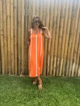 Vestido midi color naranja con rayas verticales blancas, de tejido de punto en hilo, con breteles anchos y corte recto.