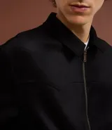 Campera marrón con cierre frontal, cuello inglés, bolsillos laterales y bajo con elástico. Presenta detalles de recortes en la parte superior. Marca Marfinno.