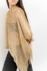Poncho tejido color cobre con apliques de piedras y flecos.