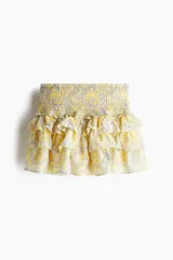 Minifalda amarilla con estampado paisley en tonos grises y cintura elastizada. Presenta volados en capas.