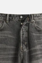Pantalón de jean negro de corte amplio, con cinco bolsillos, efecto lavado y cierre frontal con cremallera y botón.
