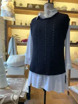 Chaleco color crudo tejido a mano en hilado 100% baby alpaca, con cuello tipo bote, hombros anchos, puntos calados en frente y espalda, y tajos laterales en el bajo.