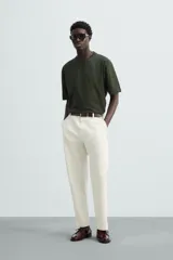 Camiseta verde oscuro de corte holgado, confeccionada en tejido de algodón grueso. Tiene cuello redondo y mangas cortas sin costura en la sisa.