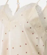 Conjunto de pijama compuesto por un top de satén color crema con lunares marrones, breteles finos regulables y escote en V con encaje, y un short con cintura elástica y estampado de lunares a juego.