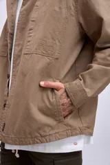 Cazadora color beige con cuello clásico, cierre frontal con botones, mangas largas y bolsillos de parche en el pecho.