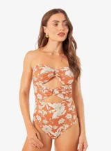 Traje de baño enterizo color ladrillo con estampado floral en blanco, diseño strapless con aberturas en la parte delantera y detalle de frunce con aro metálico.