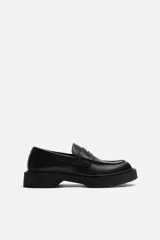 Mocasín negro de cuero con antifaz, forro y plantilla interior a tono, horma redonda y suela con volumen y textura.