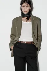 Pantalón de vestir color beige, de tiro alto y corte recto. Incluye cinturón marrón con hebilla metálica. Presenta bolsillos laterales y falsos bolsillos traseros de doble vivo. Cierre frontal con cremallera, botón interior y gancho oculto.