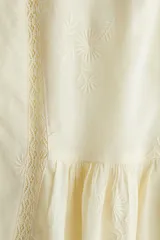 Vestido corto color crema en tejido liviano de algodón con inserciones de encaje, escote en V y mangas largas abullonadas con elástico en la muñeca y puños acampanados.