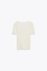 Camiseta color crema de tejido de punto rib, corte slim fit, escote en pico con detalle de encaje y mangas cortas.