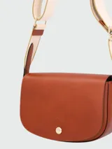 Bandolera Longchamp modelo Épure, color verde oliva, con correa de tela ajustable y cierre con botón a presión.