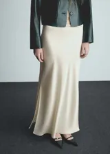 Falda maxi color crema de tejido satinado con goma elástica en la cintura y abertura lateral.
