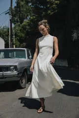 Vestido largo color blanco, de cuello redondo y sin mangas. Tejido con textura y corte evasé con vuelo.