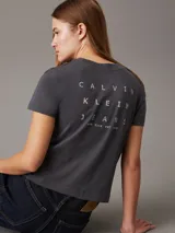 Remera gris de algodón con cuello redondo, mangas cortas y corte crop. Logo de Calvin Klein bordado en el pecho y estampado en la espalda.