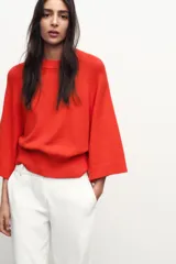 Sweater de punto color naranja con cuello redondo y mangas anchas hasta el codo.