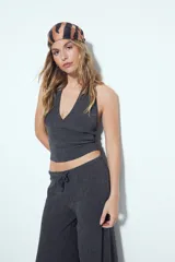 Top de cuello halter color gris oscuro, con escote en V pronunciado en el frente y espalda descubierta. Presenta textura acanalada.