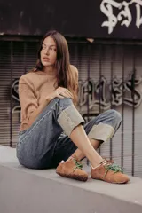 Zapatillas urbanas de cuero color tostado, con cordones verdes y suela de goma.