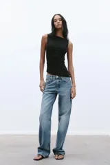 Musculosa negra con cuello barco, sin mangas, detalle de pliegues laterales y bajo asimétrico.