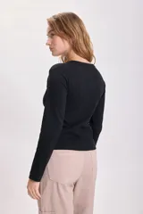 Remera negra de tejido rib con mangas largas y cuello redondo.