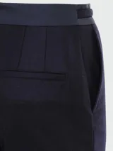 Pantalón de vestir azul marino de lana, con corte recto, bolsillos laterales y trabillas para cinturón. Presenta un cinturón fino con hebilla circular dorada.