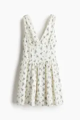 Vestido corto de algodón color blanco con estampado de pequeñas flores negras, escote en V, breteles anchos y falda con vuelo.