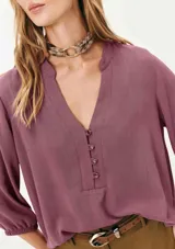 Blusa color verde claro, de mangas 3/4 con elástico en los puños, escote en V con botones y corte holgado.