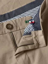 Pantalón chino de sarga color beige, corte regular, con cierre de cremallera y botón.