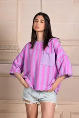Buzo de manga 3/4 con bolsillo. Estampado a rayas verticales lilas y violetas con terminaciones desflecadas.