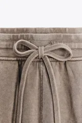 Shorts de tiro alto confeccionados en tejido con efecto lavado, cintura elástica ajustable con cordones, bolsillos laterales de vivo y tejido combinado en rib a tono.