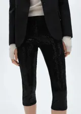 Calzas capri negras cubiertas de lentejuelas, con cintura elástica y corte skinny.